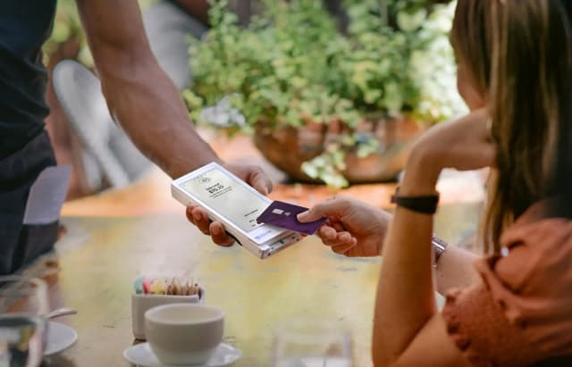 Close-up of a mobile payment transaction using a smartphone and credit card at a café table