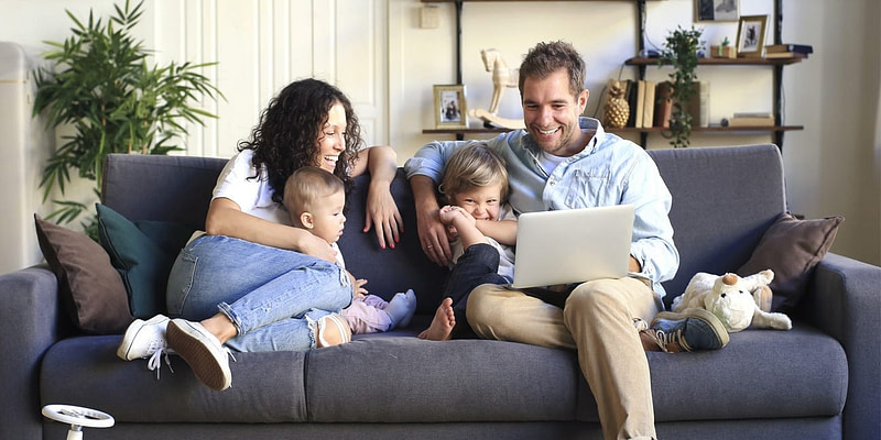 Young happy family relaxing together at home as both parents take PTO