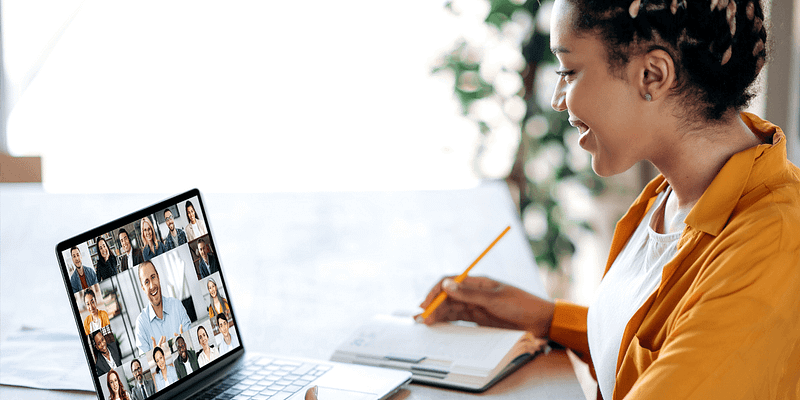 Young professional female on a video conference call with coworkers, taking notes