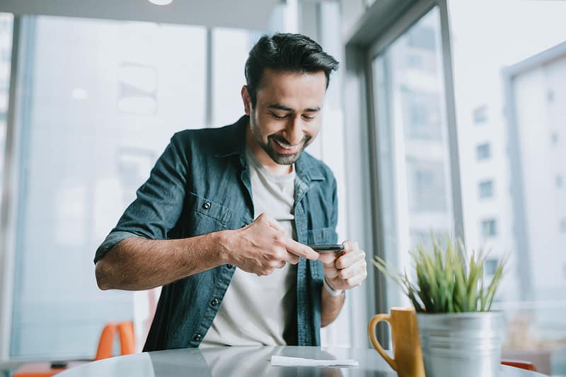 A smiling young Indian man using his smart phone