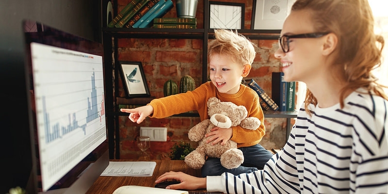 Young mother working from home as her son ask about data analysis on her computer screen