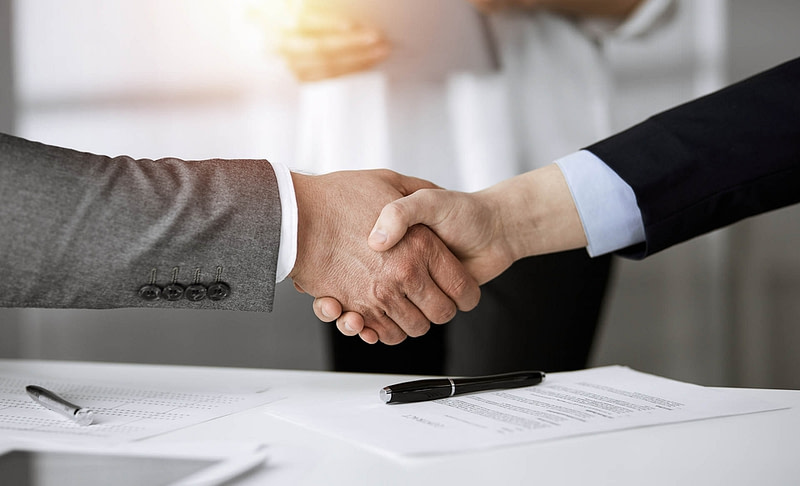 Business people shaking hands finishing contract signing in sunny office, close-up. Handshake and marketing