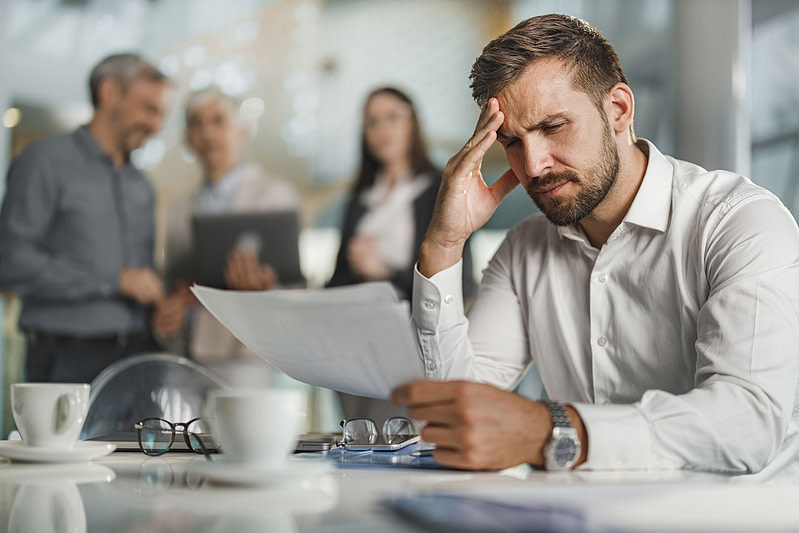 Worried businessman going through paperwork in the office.