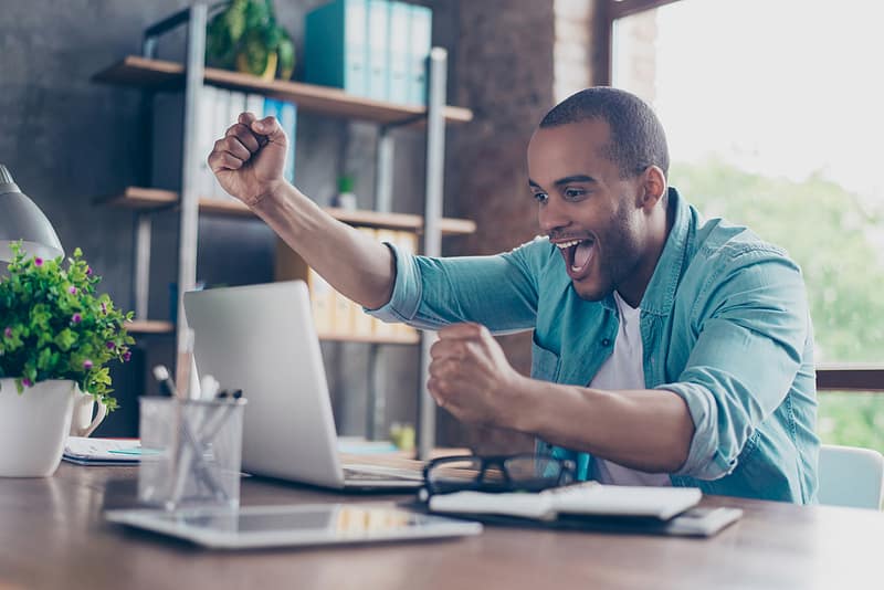 young afro american entrepreneur excited in front of his laptop